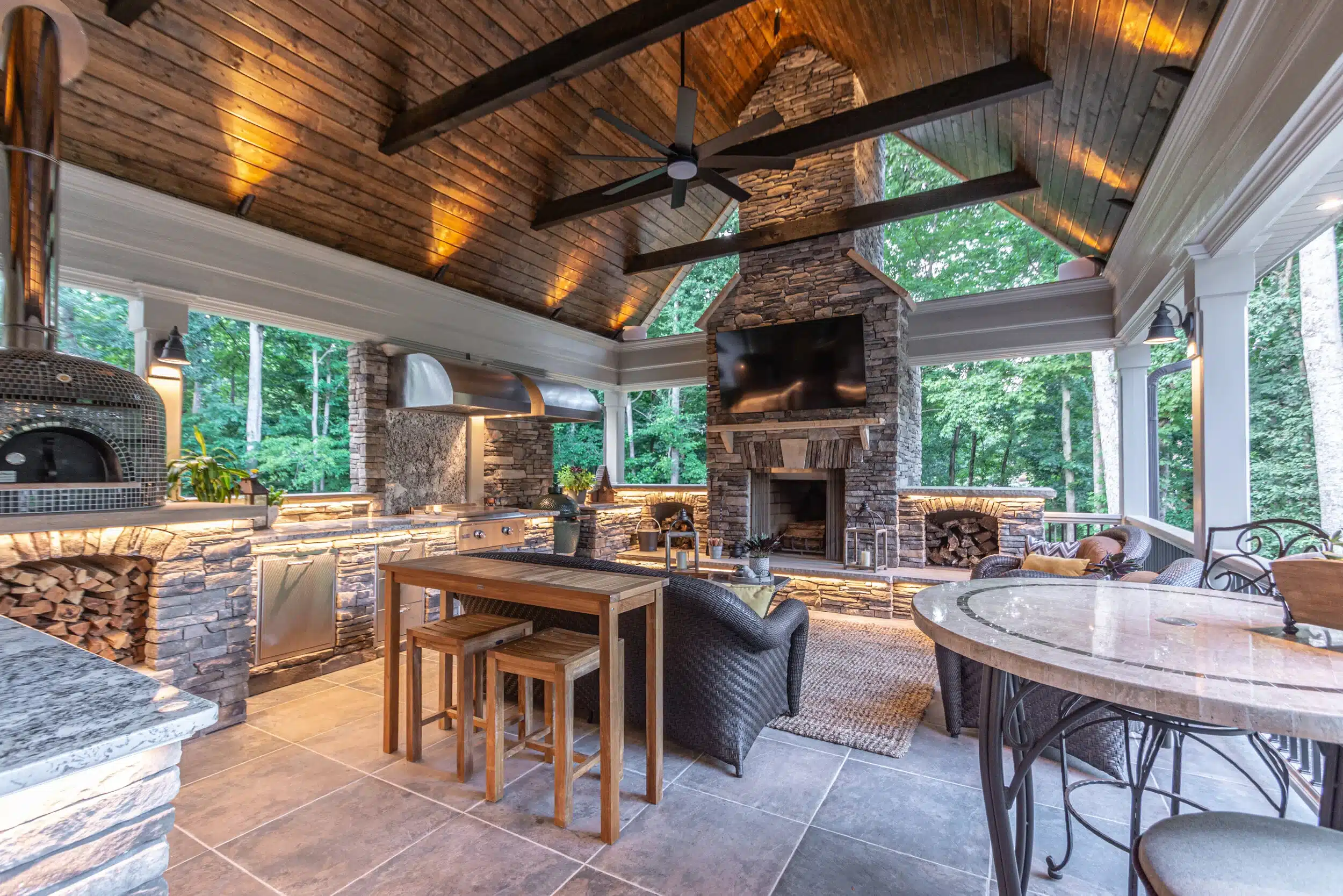 A luxury outdoor kitchen in Atlanta featuring a built-in stainless steel grill, stacked stone island, and granite countertops integrated into a custom stone patio.